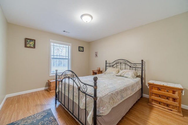 bedroom with visible vents, baseboards, and wood finished floors