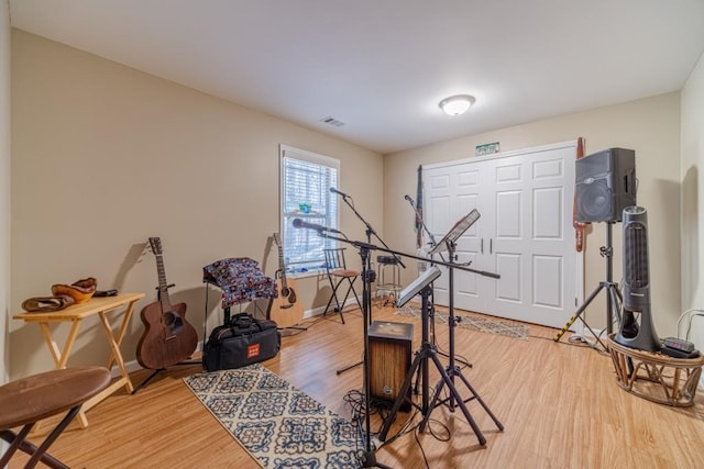 exercise area featuring light wood-style floors, baseboards, and visible vents