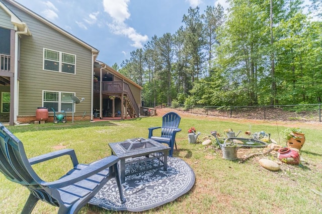 view of yard with a deck, fence, a fire pit, and stairs