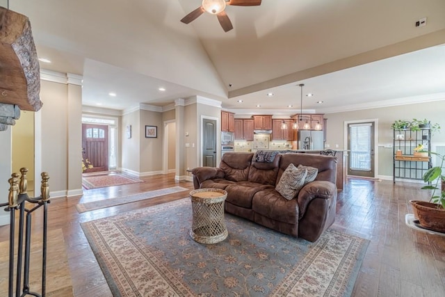 living area featuring crown molding, baseboards, ceiling fan, and vaulted ceiling
