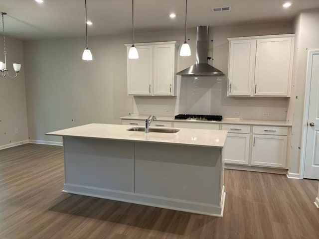 30 Riverrock Trl, Dallas, GA 30157 - kitchen with wall chimney range hood, wood finished floors, gas stovetop, a kitchen island with sink, and light countertops