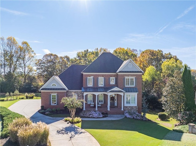 view of front facade featuring covered porch, concrete driveway, a front lawn, and brick siding