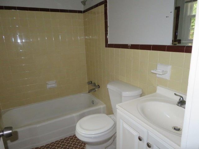 full bathroom with tiled shower / bath, tile walls, vanity, and toilet