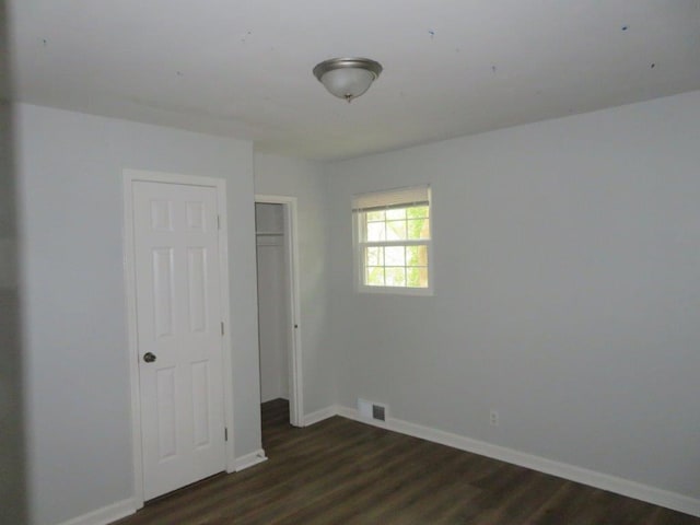 unfurnished bedroom featuring dark hardwood / wood-style flooring and a closet