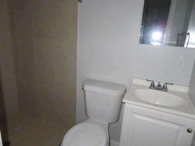 bathroom featuring vanity, tiled shower, and toilet