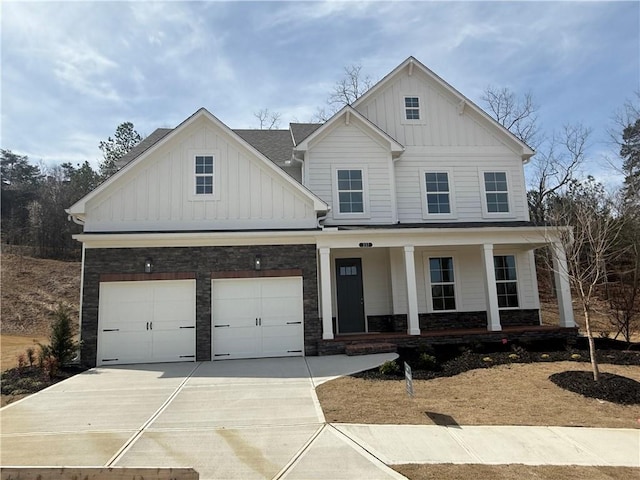 view of front of property featuring covered porch, concrete driveway, board and batten siding, and stone siding