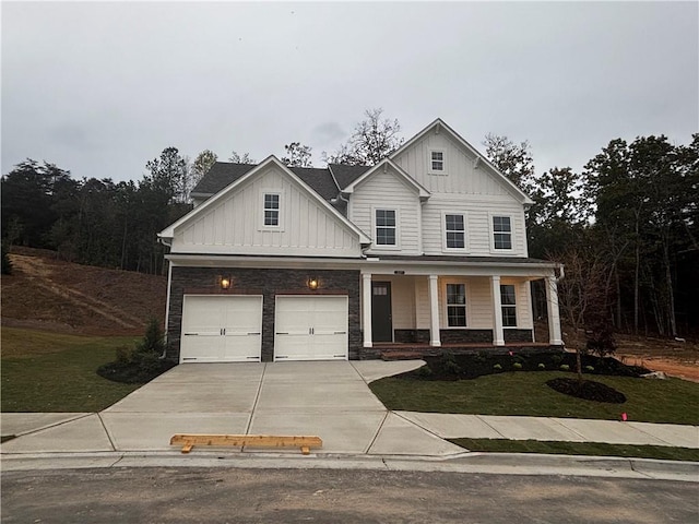 view of front of property featuring a garage, a porch, and a front lawn