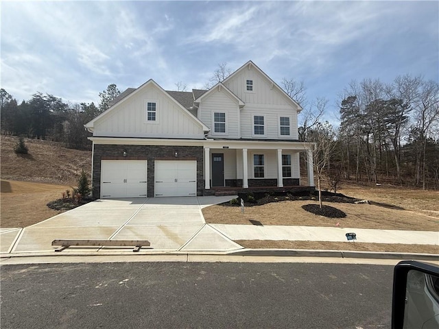 view of front facade with covered porch, a garage, driveway, stone siding, and board and batten siding