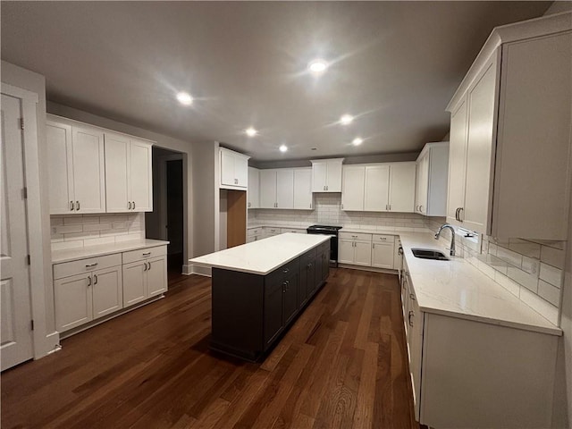 kitchen featuring sink, stainless steel stove, dark hardwood / wood-style floors, a kitchen island, and white cabinetry