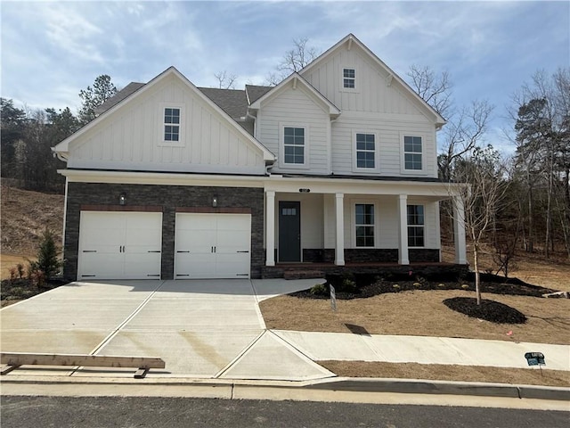 view of front facade featuring board and batten siding, concrete driveway, a porch, and stone siding