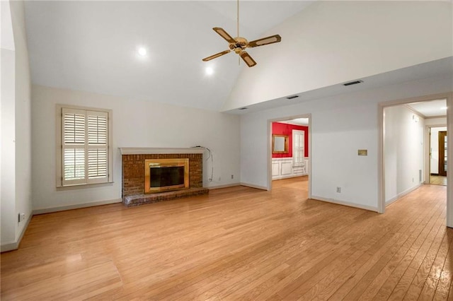 unfurnished living room featuring ceiling fan, high vaulted ceiling, a fireplace, and light hardwood / wood-style floors