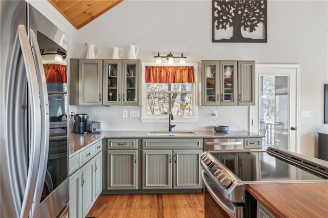 kitchen featuring a sink, stainless steel appliances, backsplash, and vaulted ceiling