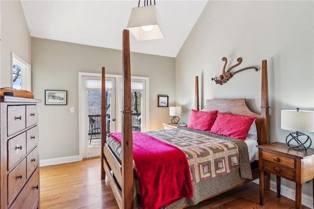 bedroom featuring multiple windows, baseboards, lofted ceiling, and light wood-style floors