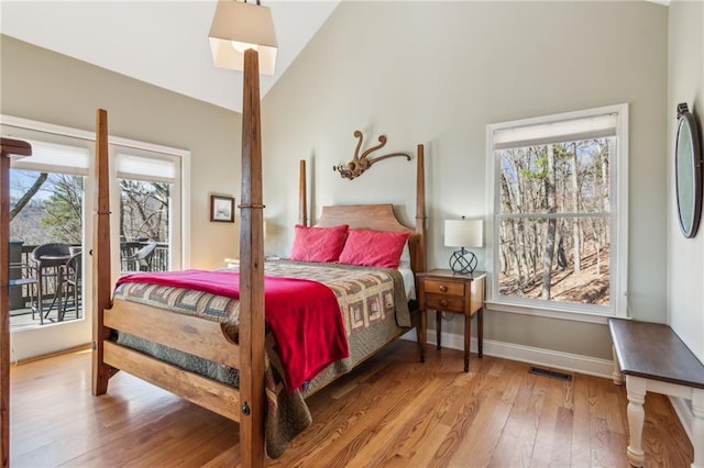 bedroom with visible vents, multiple windows, wood finished floors, and access to exterior