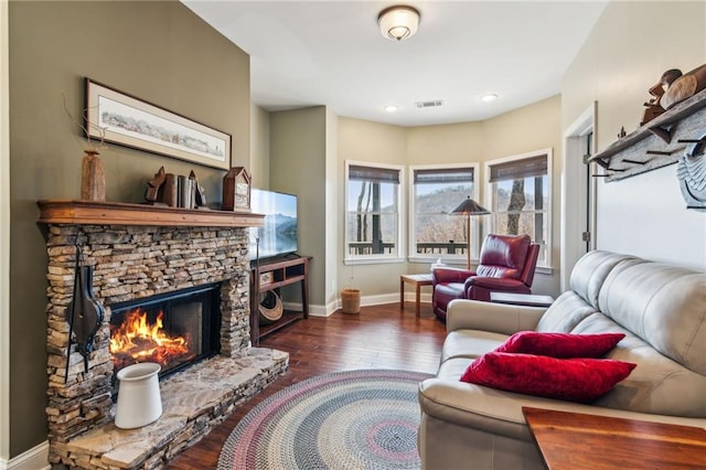 living room featuring visible vents, a fireplace, baseboards, and hardwood / wood-style flooring