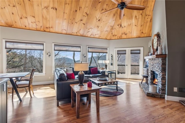 living room with a stone fireplace, french doors, wood ceiling, and wood finished floors