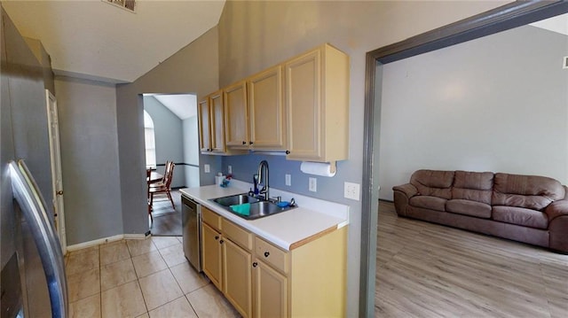 kitchen featuring a sink, light countertops, baseboards, appliances with stainless steel finishes, and lofted ceiling