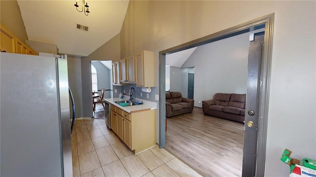 kitchen with a sink, stainless steel appliances, visible vents, light countertops, and open floor plan