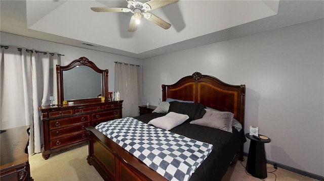 bedroom with a raised ceiling, ceiling fan, light carpet, and visible vents