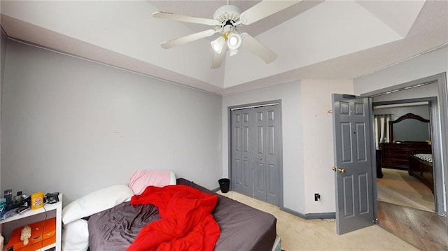 bedroom with baseboards, a ceiling fan, light carpet, and a closet