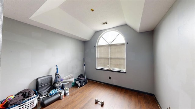 unfurnished room featuring visible vents, vaulted ceiling, wood finished floors, and baseboards