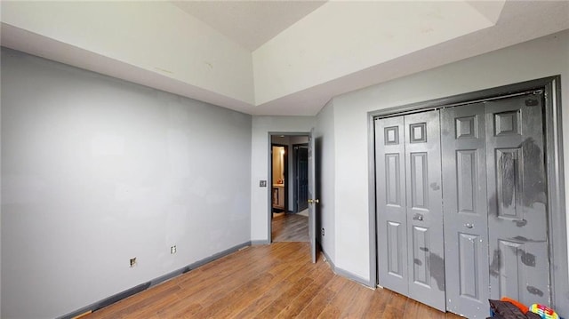 unfurnished bedroom with baseboards, a closet, and light wood-style flooring