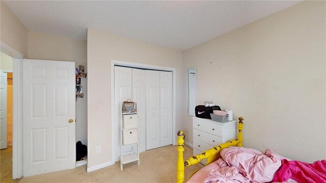 bedroom featuring baseboards, a closet, and light colored carpet
