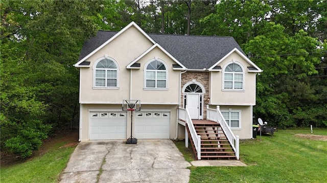 split foyer home featuring an attached garage, concrete driveway, a front yard, and stucco siding