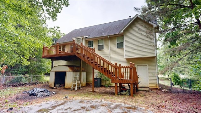 back of property with stairs, a storage unit, a deck, central AC unit, and a fenced backyard