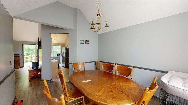 dining area featuring high vaulted ceiling, wood finished floors, and a notable chandelier