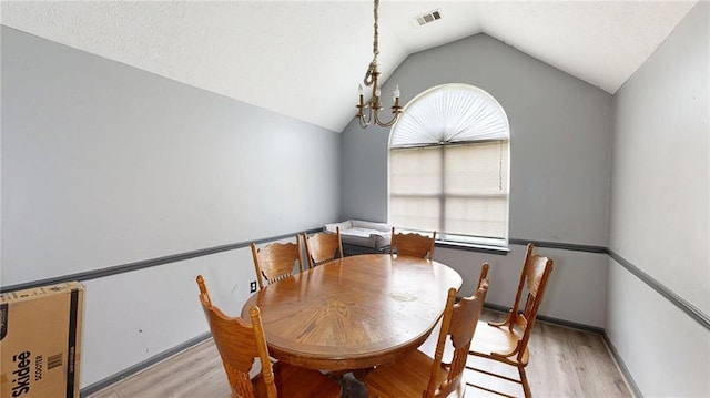 dining room featuring light wood-style floors, plenty of natural light, vaulted ceiling, and visible vents