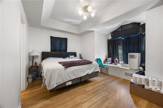 bedroom featuring a tray ceiling and light hardwood / wood-style floors