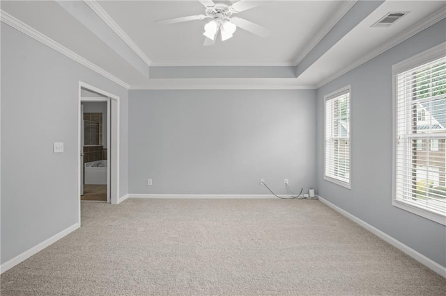 unfurnished room with a tray ceiling, crown molding, and visible vents