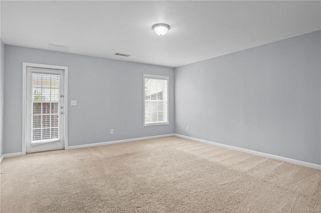 unfurnished room featuring light colored carpet, visible vents, and baseboards