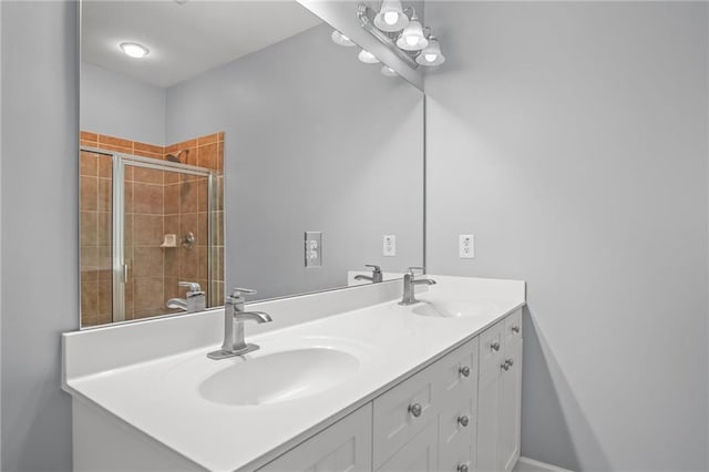 bathroom featuring double vanity, a tile shower, and a sink