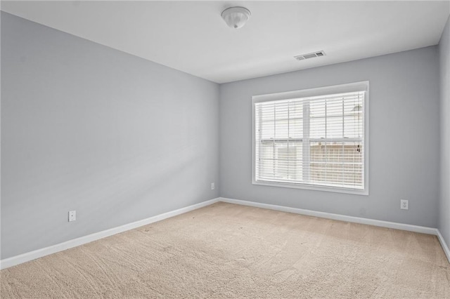 empty room with carpet flooring, visible vents, and baseboards