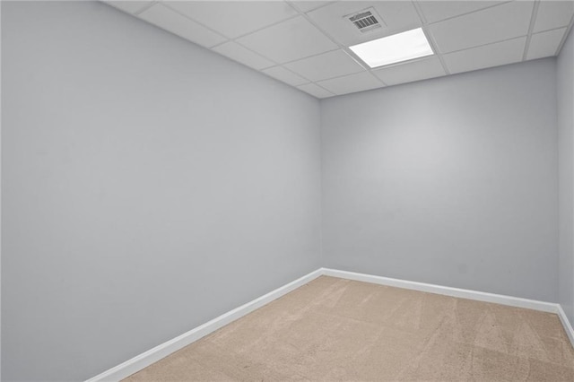 carpeted spare room featuring a paneled ceiling, visible vents, and baseboards