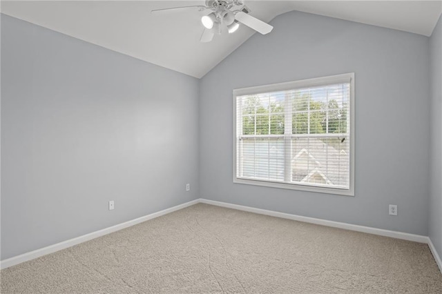 carpeted spare room with baseboards, a ceiling fan, and vaulted ceiling