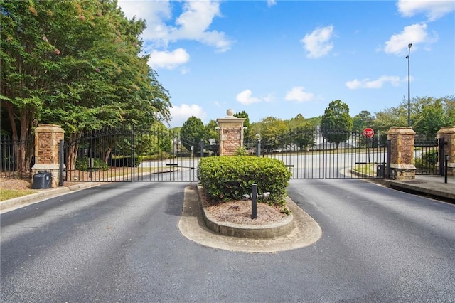 view of street featuring a gated entry, curbs, street lights, and a gate