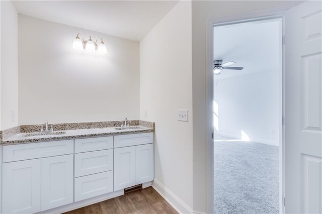 bathroom with double vanity, ceiling fan, baseboards, and a sink