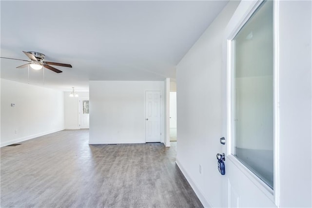 unfurnished living room featuring ceiling fan, visible vents, baseboards, and wood finished floors