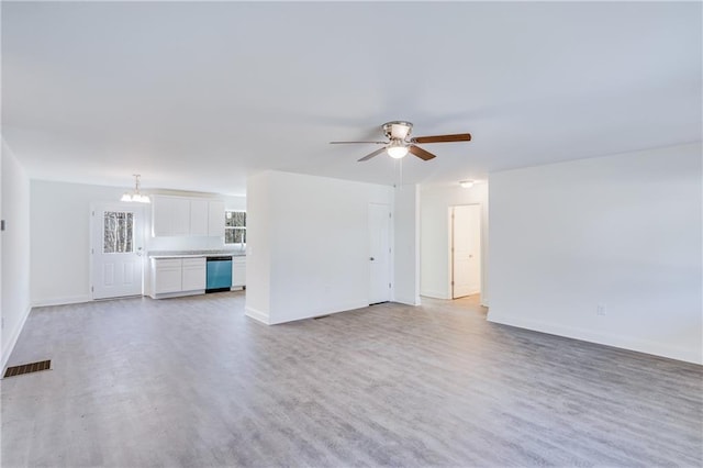 unfurnished living room featuring light wood-style flooring, visible vents, baseboards, and ceiling fan with notable chandelier