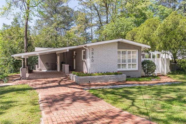 view of front of house featuring brick siding, a front lawn, and fence