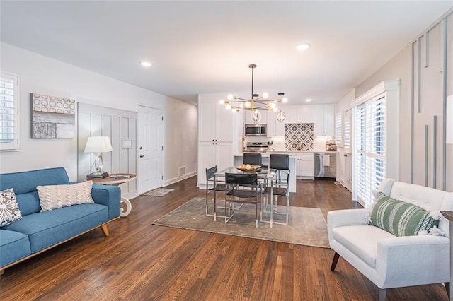 living area with dark wood-style flooring, recessed lighting, and an inviting chandelier