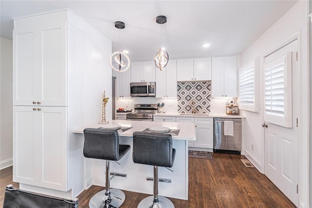 kitchen with white cabinets, dark wood finished floors, light countertops, and appliances with stainless steel finishes