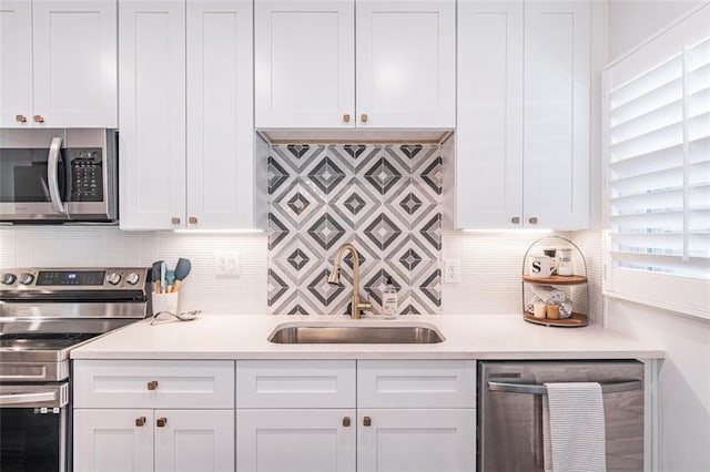 kitchen with stainless steel appliances, light countertops, a sink, and white cabinetry