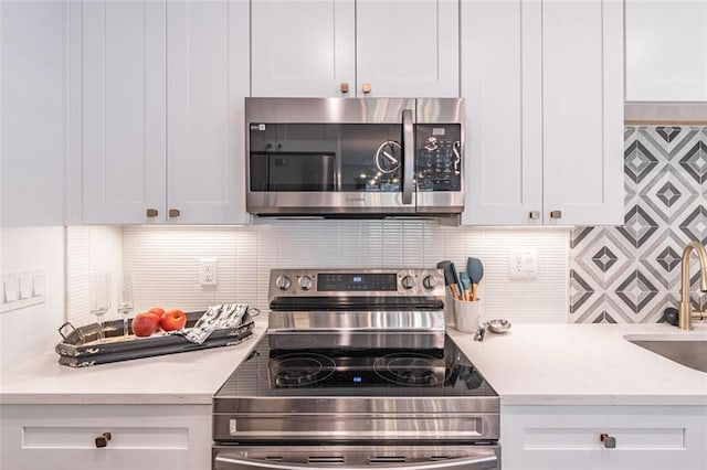kitchen with white cabinetry, a sink, backsplash, and stainless steel appliances