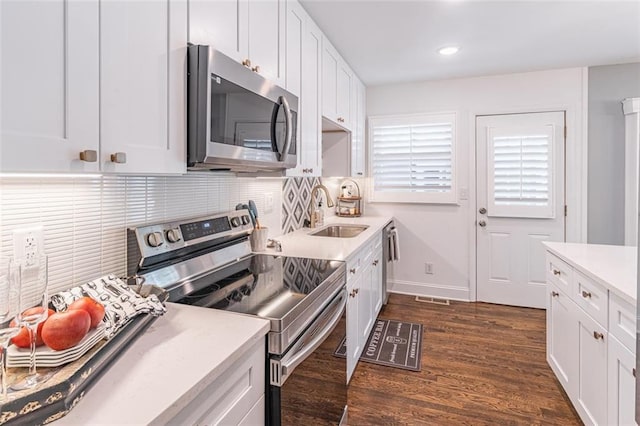 kitchen with dark wood-type flooring, a sink, white cabinetry, and stainless steel appliances
