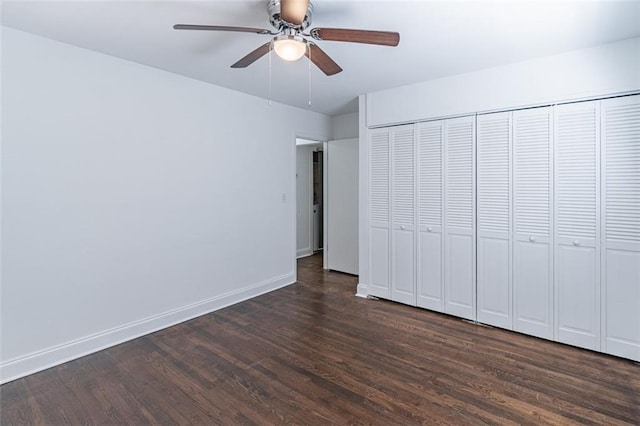 unfurnished bedroom featuring a closet, dark wood-style floors, baseboards, and ceiling fan