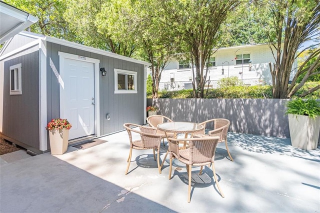 view of patio / terrace with an outbuilding, outdoor dining space, and a storage shed